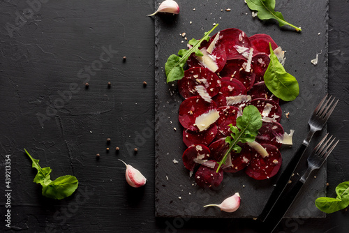 Young beet carpaccio with parmesan, nuts, arugula and garlic with olive oil. Vegan food.