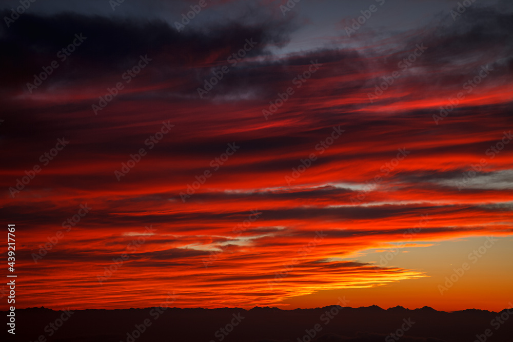 遥か西方の北アルプスが地平線を描くその上空に赤く焼けた雲が折り重なるように並んでいく