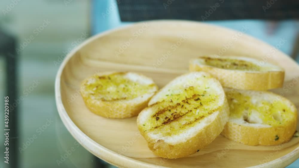 Close up with blurred background of homemade prepared toasted bread with butter spread served on table for breakfast in morning shows people hand picking for appetizer food of tasty meal. Close up with blurred background of homemade prepared toasted bread with butter spread served on table for breakfast in morning shows people hand picking for appetizer food of tasty meal.