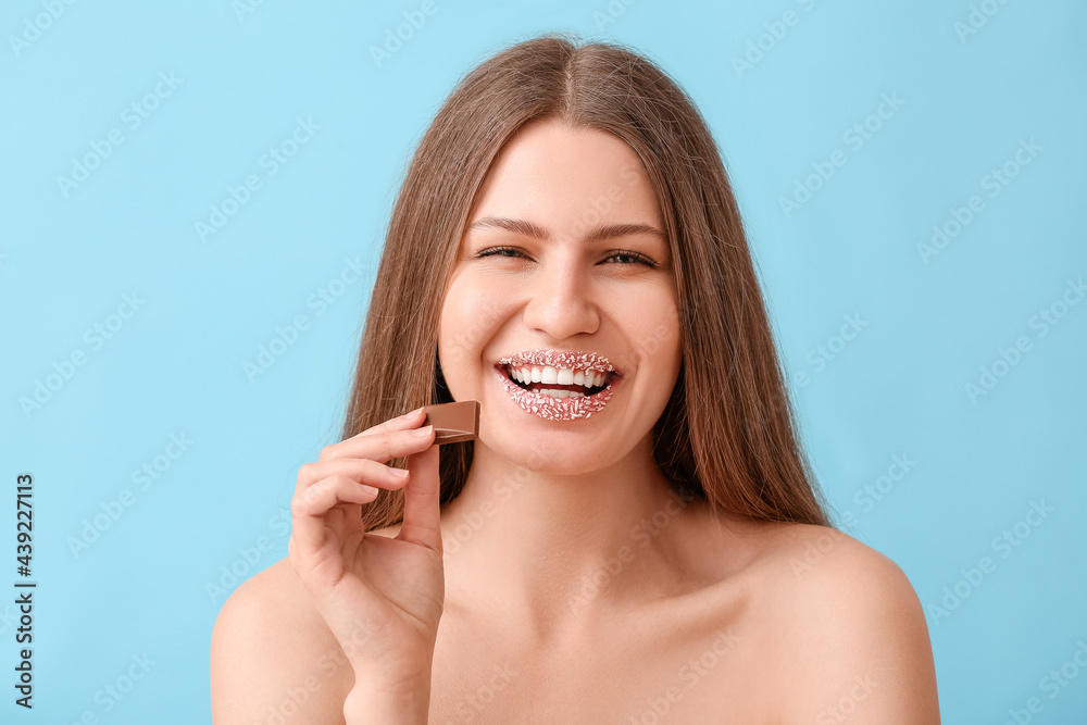 Beautiful young woman with creative makeup and sweet chocolate on color background Beautiful young woman with creative makeup and sweet chocolate on color background