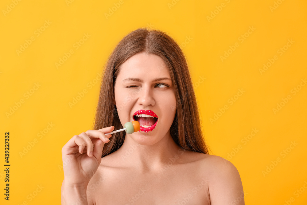 Beautiful young woman with creative makeup and sweet lollipop on color background Beautiful young woman with creative makeup and sweet lollipop on color background