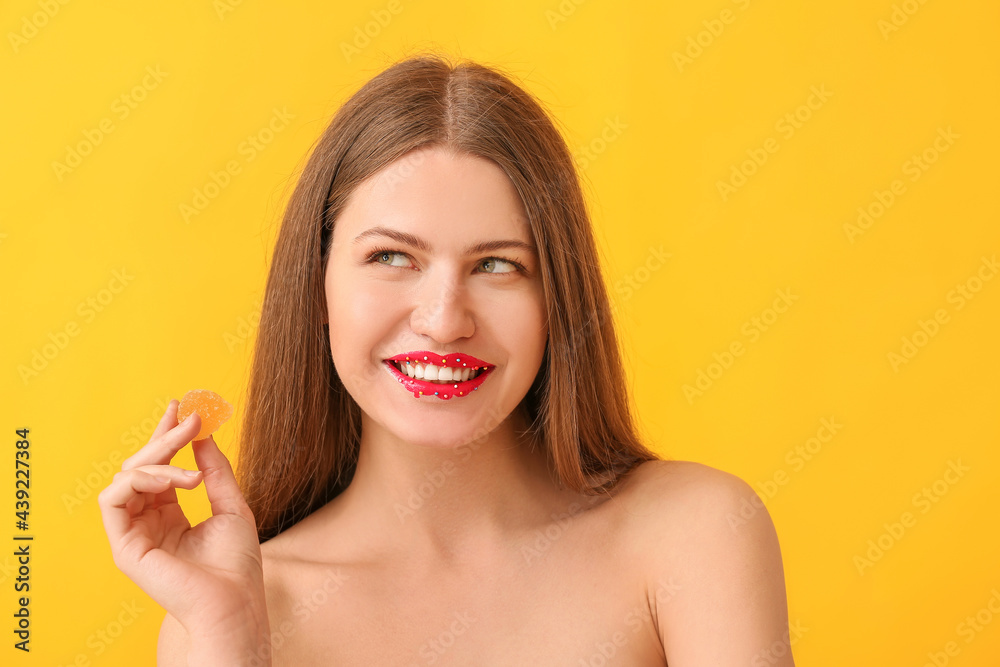Beautiful young woman with creative makeup and candy on color background Beautiful young woman with creative makeup and candy on color background