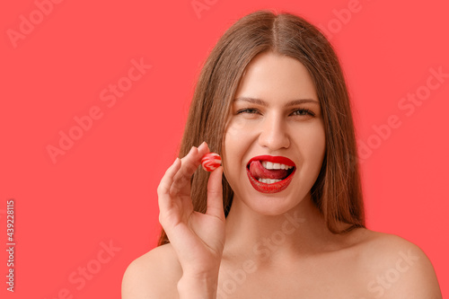 Beautiful young woman with sweet candy on color background
