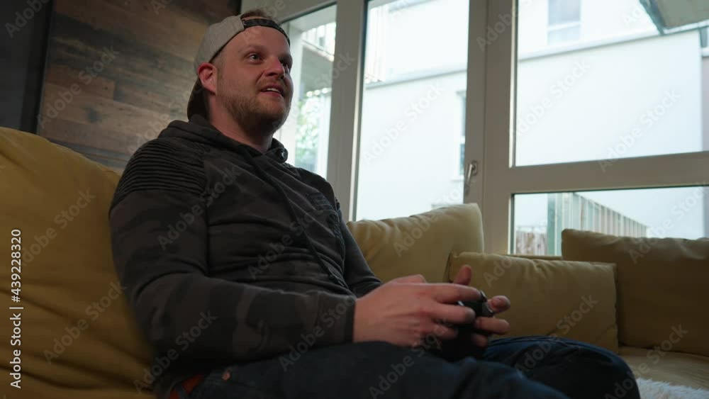 GAMING - Excited millennial man playing a video game, low angle medium shot GAMING - Excited millennial man playing a video game, low angle medium shot