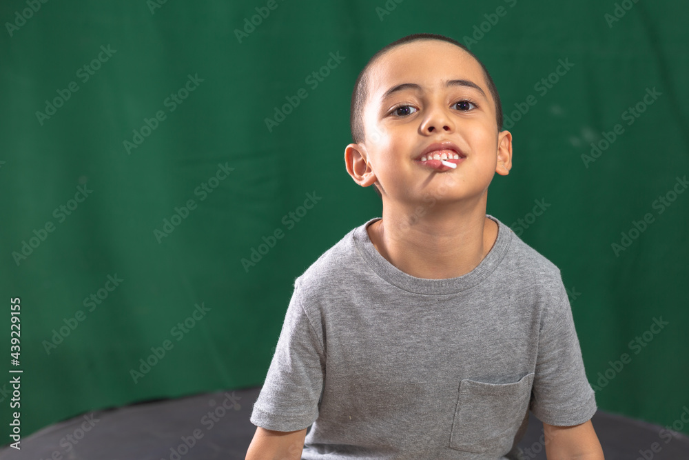 Cute caucasian young kid holding yellow lollipop showing broken milk tooth..Studio portrait, concept health with dark green background..boy in smiling face,cheeky face and funny posting.