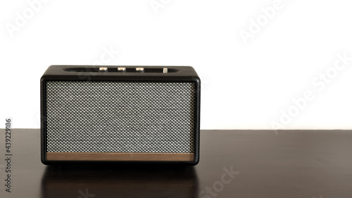 Wireless Bluetooth portable speaker on wooden table on white background.