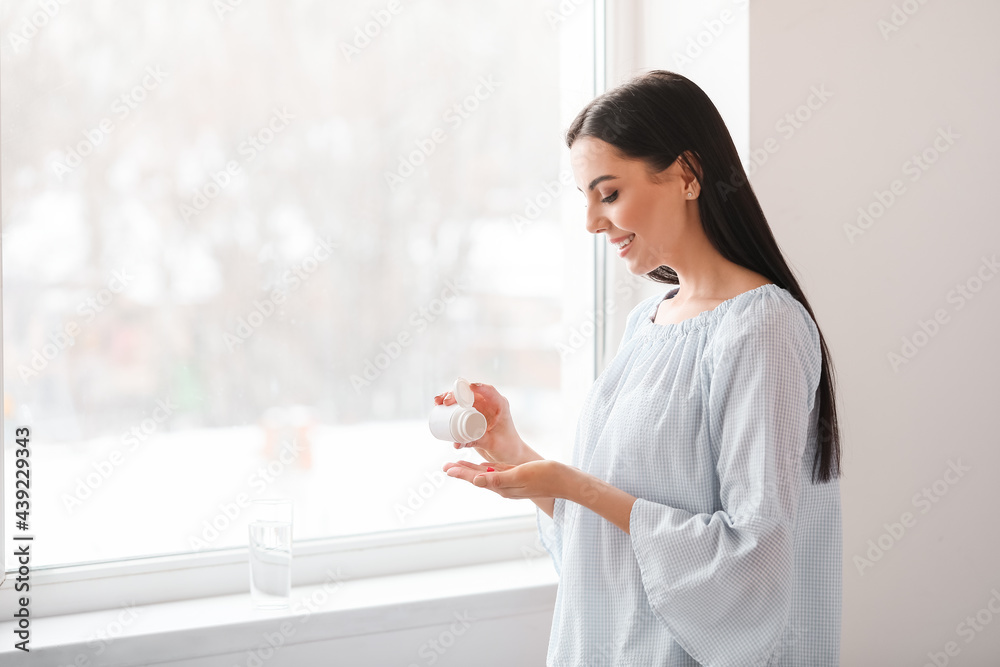 Beautiful young woman taking pills at home Beautiful young woman taking pills at home
