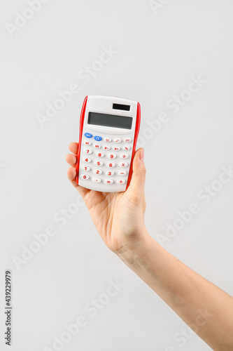 Woman with calculator on light background