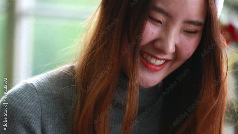 Slow-motion and close up portrait of young beautiful Asian women wearing Santa hat smiling and enjoying herself during holiday Slow-motion and close up portrait of young beautiful Asian women wearing Santa hat smiling and enjoying herself during holiday