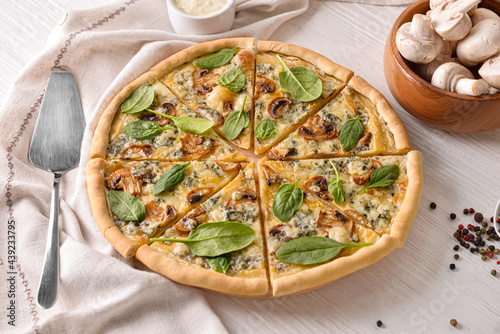 Tasty vegetarian pizza with mushrooms and spinach on wooden table