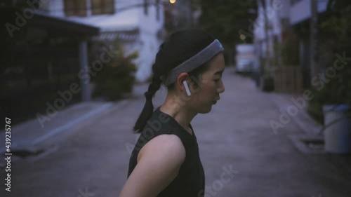 Young Asian 30s female runner stretching and exercising in neiborhood street in Thailand. Sweaty woman wearing sportswear for outdoor workout photo