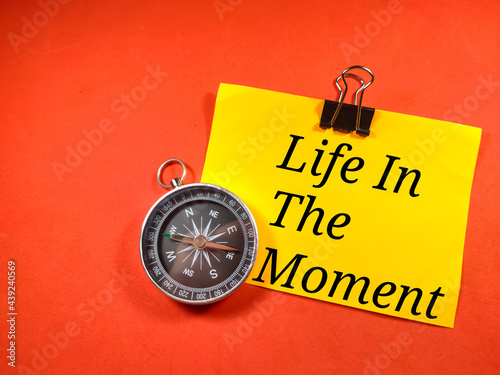Education concept.Text Life in the moment on colorful paper note with compass on red background.