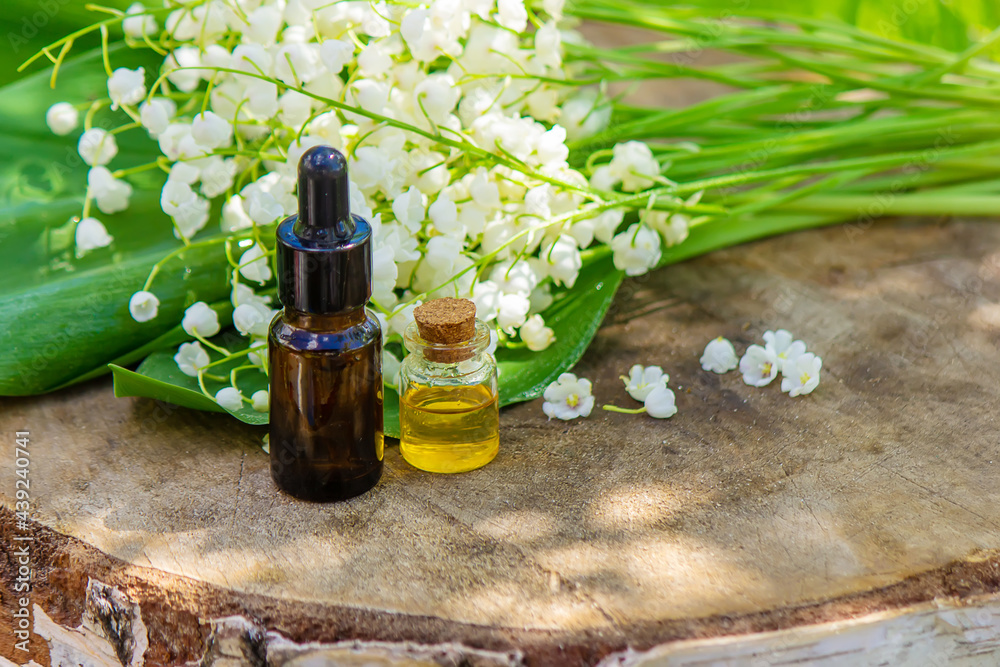 Lily of the valley essential oil in a small bottle. Selective focus. Lily of the valley essential oil in a small bottle. Selective focus.