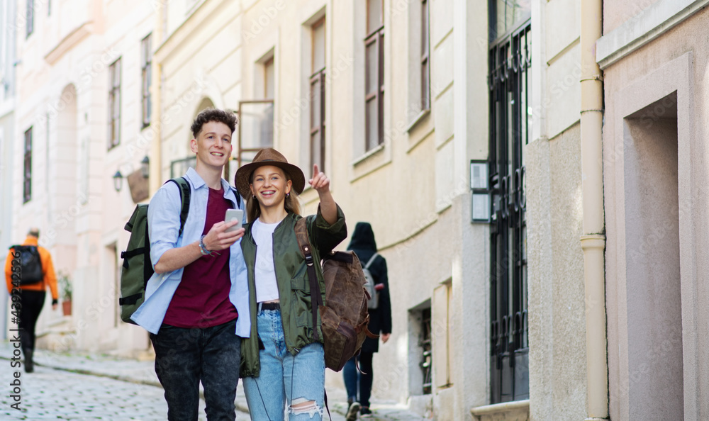 Obraz premium Young couple travelers using smartphone in city on holiday, sightseeing.