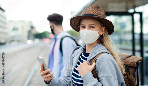 Young woman tourist traveler on holiday waiting at the bus stop in city, coronavirus concept. photo