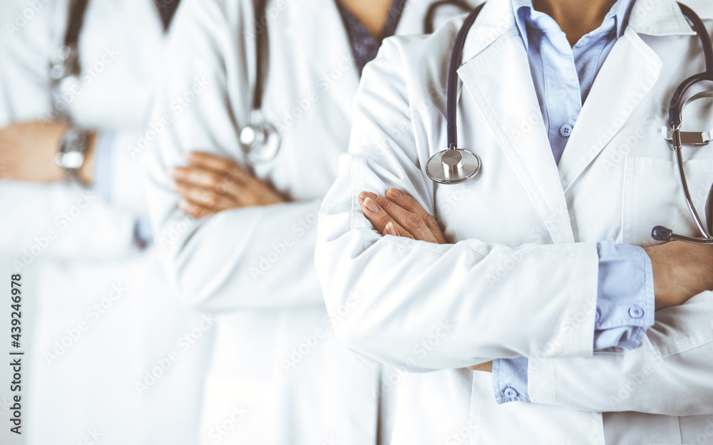 Group of modern doctors standing as a team with arms crossed in hospital office and ready to help patients. Medical help, insurance in health care, best disease treatment and medicine concept Group of modern doctors standing as a team with arms crossed in hospital office and ready to help patients. Medical help, insurance in health care, best disease treatment and medicine concept