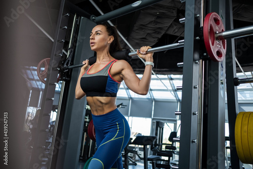 Young woman performing lunges on Smith machine at gym
