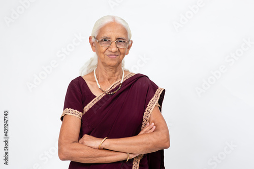 Elderly Indian woman standing with her arms folded. Senior woman smiling and looking into the camera