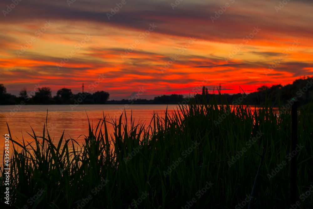 Crimson sunset over the river on a summer day