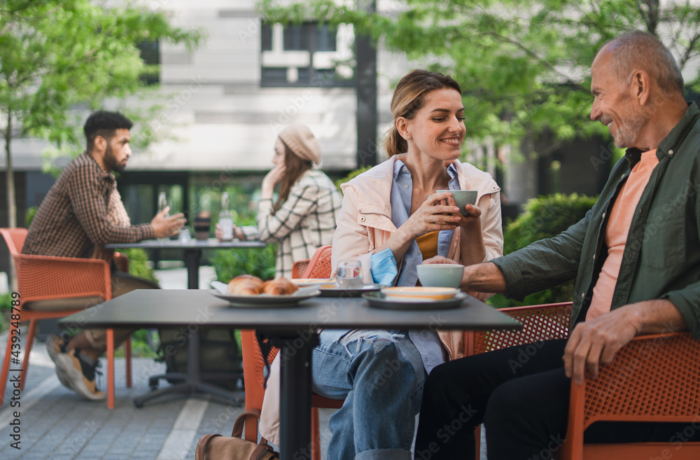 Woman with senior father in cafe outdoors in city, life after covid-19 vaccination and back to normal concept. Woman with senior father in cafe outdoors in city, life after covid-19 vaccination and back to normal concept.