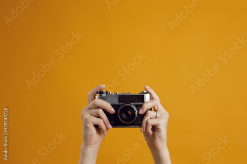 Classic 35mm old analog camera on yellow background. Hands of a girl with a camera, a place to copy.