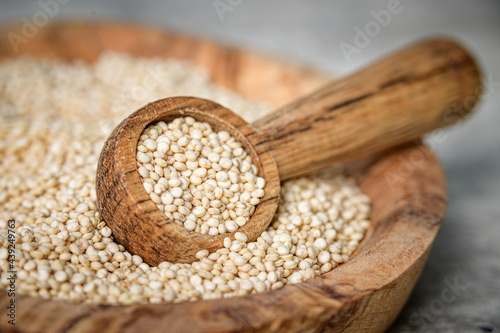Raw white quinoa seeds on wooden spoon