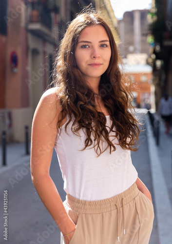 Portrait of a positive confident girl, standing in good weather on the street