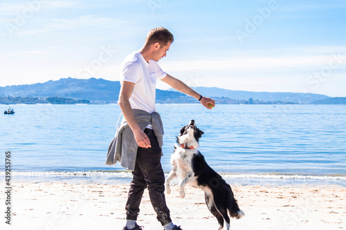 relaxed young man playing with dog on the beach