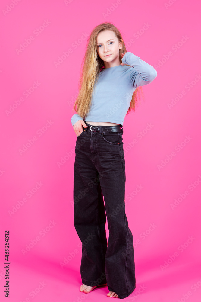 Full Length Portrait of Caucasian Teenage Girl In Casual Street Clothing Against Pink Background. Full Length Portrait of Caucasian Teenage Girl In Casual Street Clothing Against Pink Background.