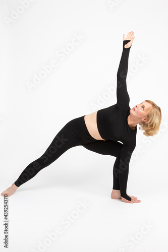Mature People Sport Concepts. Mature Caucasian Woman Practicing Yoga Asana Pose In Professional Sport Gear Over White Background.