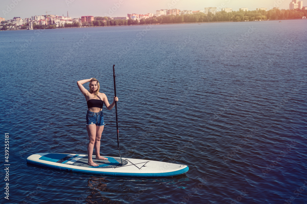 Charm young woman on paddle board SUPat the city lake