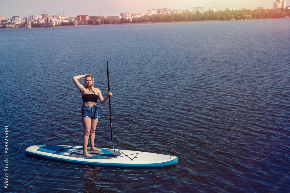 Charm young woman on paddle board SUPat the city lake Charm young woman on paddle board SUPat the city lake