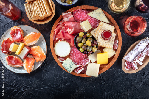 Charcuterie and cheese platter, overhead flat lay shot on a black background with a place for text. Italian antipasti or Spanish tapas, shot from above with wine and olives Mediterranean delicatessen