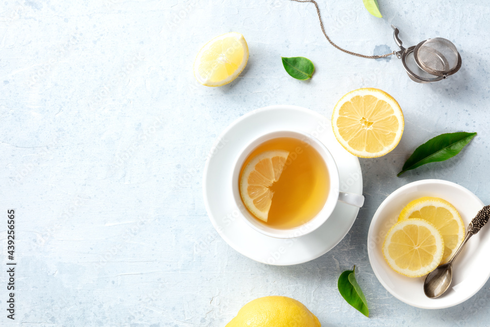 Lemon tea in a cup, shot from the top with copy space. Organic lemons, green leaves and the natural remedy of the healthy drink