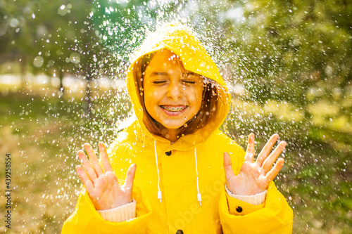 smiling teenage girl wearing raincoat outdoors in rainy day photo