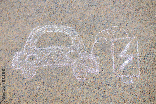 Little girl with creative craft hobby drawing electro on the asphalt with chalk car environment, eco friendly, save energy in park at summer day