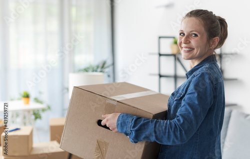 Happy woman carrying boxes in her new home