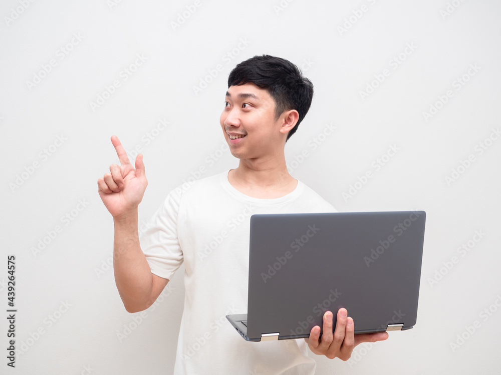 Asian man cheerful holding laptop point finger at space white background Asian man cheerful holding laptop point finger at space white background
