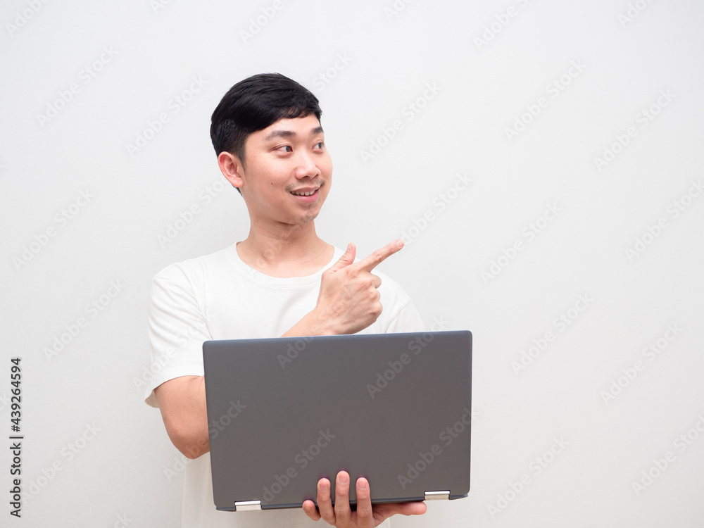 Asian man cheerful holding laptop point finger at space white background Asian man cheerful holding laptop point finger at space white background