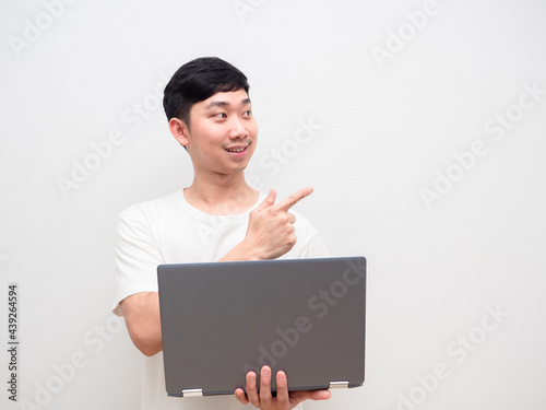 Asian man cheerful holding laptop point finger at space white background