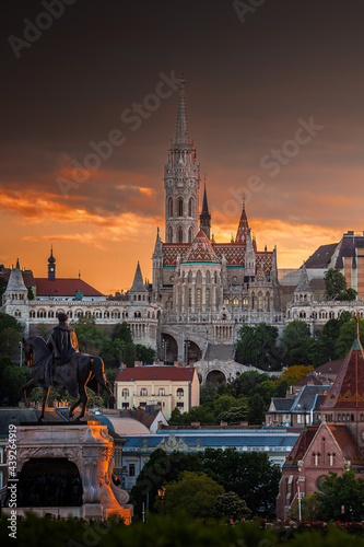 Budapest, Hungary - St Matthias Church and Fisherman's Bastion (Halaszbastya) with Statue of Gyula Andrassy in foreground and beautiful golden sunset and dramatic sky on a summer afternoon