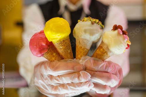 Commessa di una gelateria mentre regge 4 piccolini coni gelato preconfezionati photo