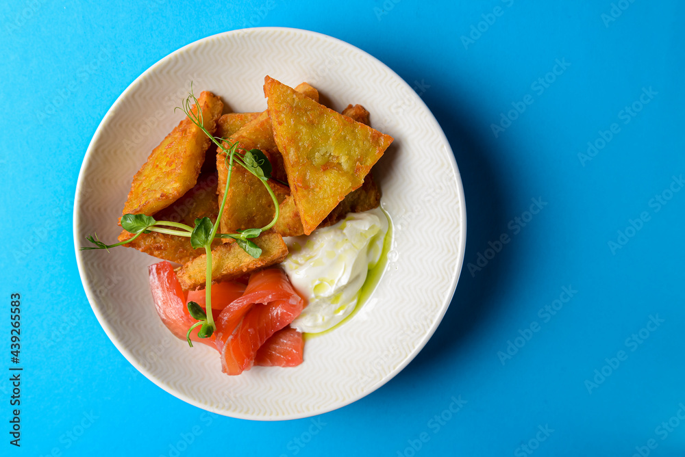 Closeup of freshly fried potato pancakes served with salmon fish and sauce.