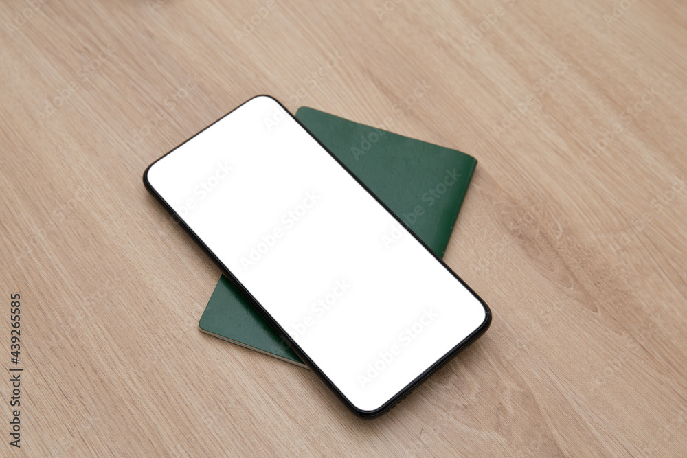 Travel concept. Photo of smartphone with white screen and passport on the table Travel concept. Photo of smartphone with white screen and passport on the table