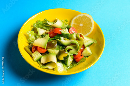 Vegetable salad made of fresh cucumbers, cherry tomatoes, avocado, lettuce salad and lemon.