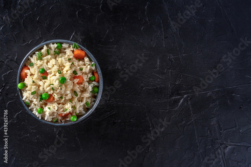 White rice with veggies, shot from the top on a black background with copy space