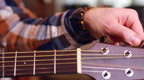 close up man playing on guitar at home learning and tune