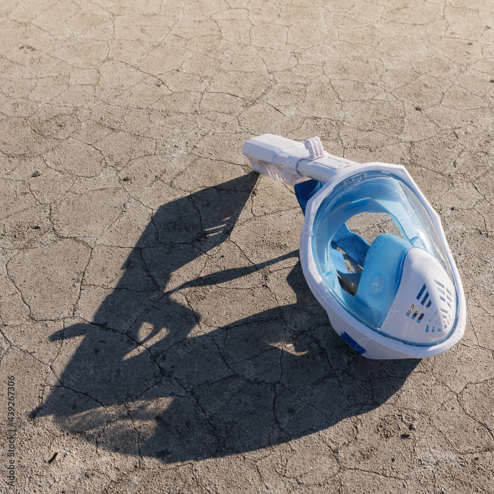 full face swim mask lying on dry, cracked ground, climate concept full face swim mask lying on dry, cracked ground, climate concept