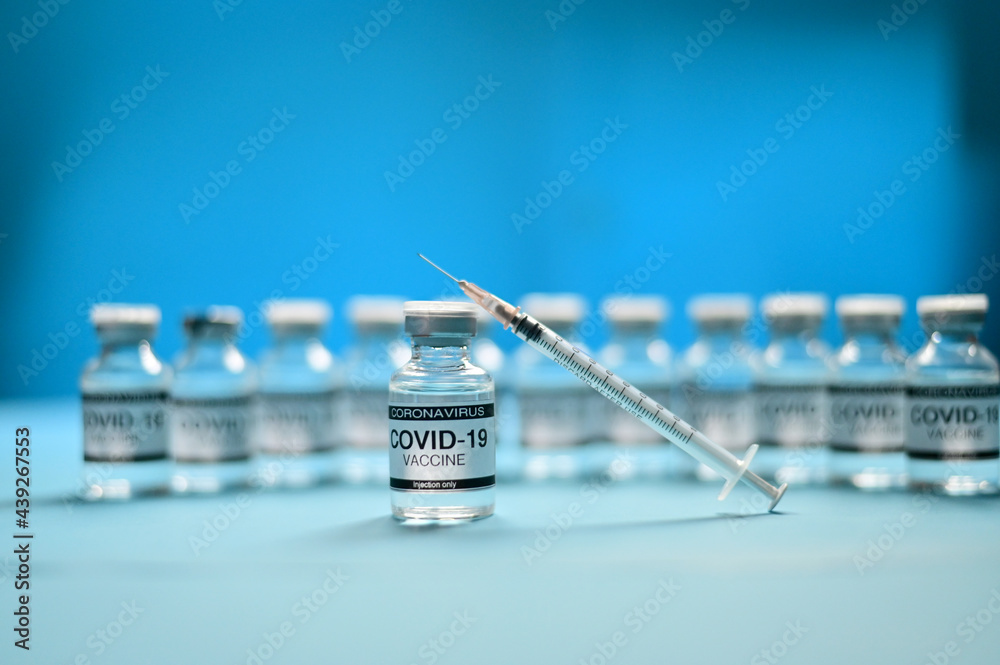 Coronavirus COVID-19 Vaccine Glass Bottle and syringe on blue surface with blue background at Thailand. Concept viruses spread throughout the world. Selective Focus. Coronavirus COVID-19 Vaccine Glass Bottle and syringe on blue surface with blue background at Thailand. Concept viruses spread throughout the world. Selective Focus.