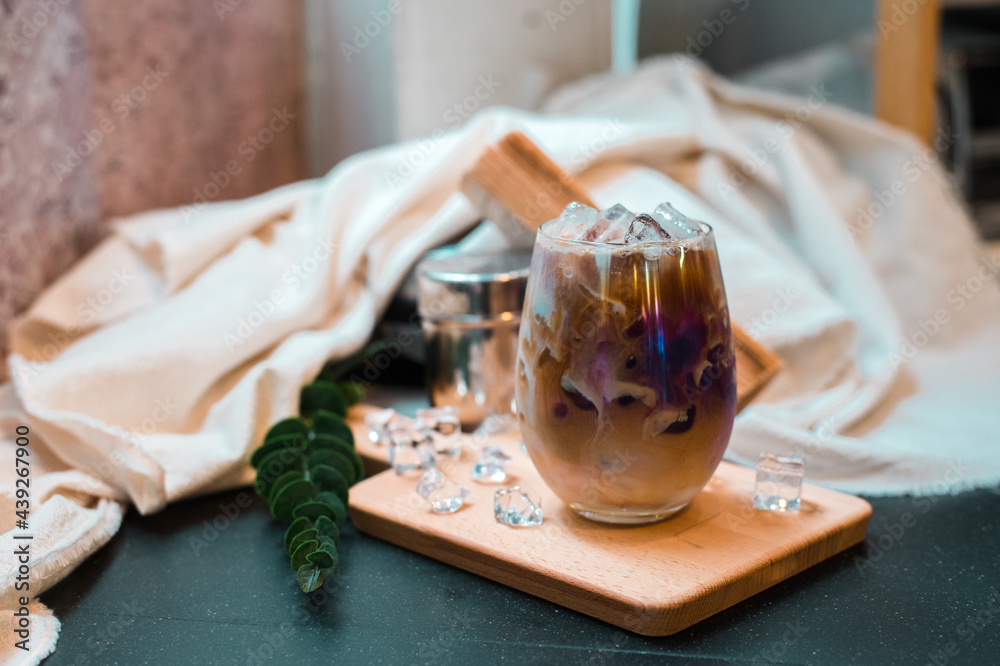 iced coffee in iridescent stemless glass served on black table at cafe​